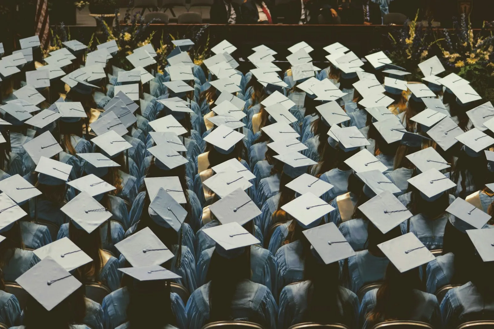 Rows of graduates in light blue gowns and mortarboards seated at a graduation ceremony
