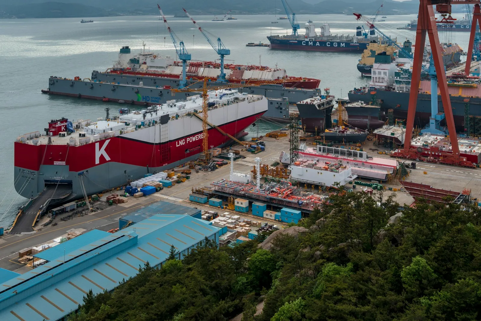 Ships under construction at a shipyard in Yeongam, South Korea, with cranes over the harbor